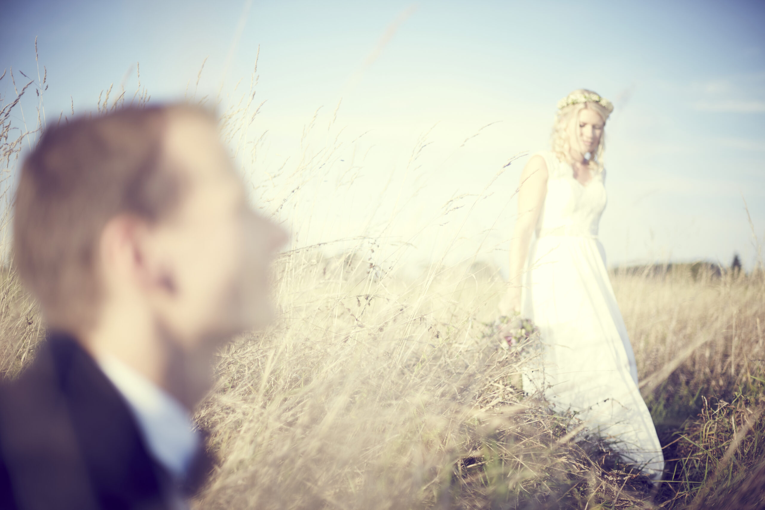 Hochzeitsporträts im Spätsommer – Braut im Feld, Bräutigam unscharf im Vordergrund